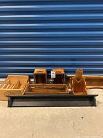 All wood items displayed lined up, showing black shelf in front, small crates and stand with heart cut out behind