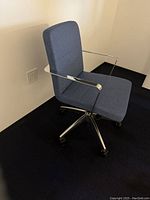 Office chair showing side view with fabric seat and backrest, chrome armrests, and chrome five-star base with casters