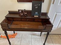 Front view of the antique wooden desk showing the top surface with small drawers and pull-out section.