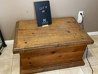 Front view of antique pine chest showing wood grain and top lid with beveled edges.