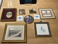 Overview photo of seven framed miniature prints and artworks arranged on a wood surface.