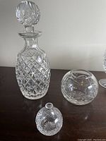 Photo showing crystal decanter with stopper and two round bowls on a table.