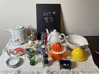 View of assorted vintage and modern breakfast-related kitchen items including teapots, juicers, and small plates arranged on a table