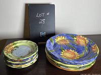 Stack of luncheon plates with orange flowers on pale green background and dinner plates with sunflower design on blue background.
