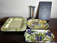 Set of three ceramic platters and one taper candle holder displayed on wooden surface