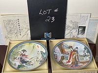 Two porcelain plates in original boxes displayed on a table with documentation and certificate behind