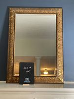 Full front view of rectangular mantle mirror with gold decorative frame and clear reflective glass.