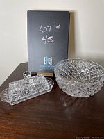Photo showing the butter dish with lid and round crystal bowl on dark wooden surface, with lot number backdrop