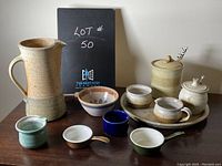 Photo of all pottery items arranged on wooden surface showing each piece in the lot.