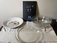 Photo showing the ceramic apple pie plate with colorful fruit illustration, clear glass Pyrex pie plate, and three nested Pyrex glass mixing bowls
