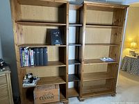 Front view of two pine shelving units side by side, displaying five shelves each, some shelves hold items that are not included.