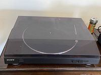 Top view of Sony turntable with clear smoked flip-top lid closed, front control buttons visible