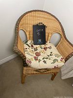 Front view of wicker chair with cushion showing diamond pattern in backrest and floral cushion.