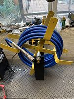 Full view of the cord reel with blue air line hose wrapped around the yellow metal frame, placed on a grey metal floor