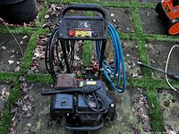 Overall front view of pressure washer showing frame, hoses and spray gun
