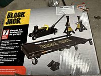 Photo of boxed Black Jack garage kit showing folding creeper, trolley jack, and jack stands graphics and branding on the packaging.