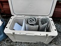Open interior of tan Sportsman cooler showing included reflective insulating mats and ice packs