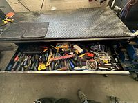 Top drawer showing assorted screwdrivers, hammers, measuring tape