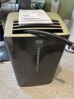 Front view of black Danby Premiere portable air conditioner showing air vents and manual on top.