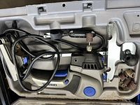 Close-up view of the Dremel Trio power tool inside its carrying case with sanding attachments and connected power cord.