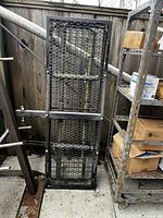 Cargo carrier folded upright leaning against fence