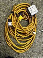 Yellow heavy duty extension cord with 4 outlet metal box, showing plugs and cord condition