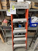 Front view of the Louisville fiberglass ladder showing orange side rails and silver rungs, with Louisville brand label on the top platform.