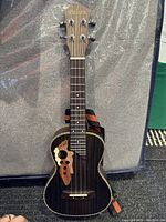 Paisen ukulele standing upright showing front face with decorative wooden sound hole area and tuning pegs visible on headstock.