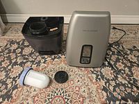 Humidifier unit, black water tank reservoir, and additional detached parts laid out on carpet.