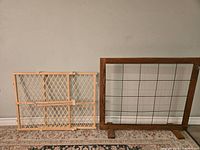 Two wooden gates side by side, one light wood lattice baby gate, one dark wood wire pet gate with sturdy feet