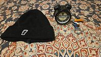 Set of three Guinness souvenir items displayed on patterned carpet showing all items clearly: black touque, mini alarm clock, and toucan fridge magnet bottle opener