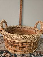 Photo of entire handmade wicker basket showing braided handles and woven design with measuring stick for scale.