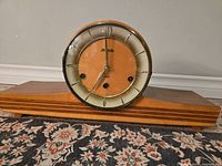 Front view of the Forestville mantle clock showing wooden base, circular face with numerals, and glass cover closed.