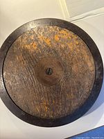 Antique wooden discus showing top surface with metal center insert and rust stains.