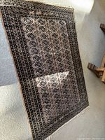 Angled view of full rug on light carpet with wooden bench legs visible