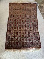 Full view of the antique wool rug showing overall pattern and shape.