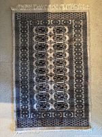 Full view of antique rectangular rug showing geometric pattern and beige background.