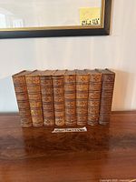 Front view of nine leather-bound volumes arranged on wood surface