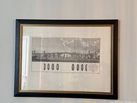 Framed 19th-century architectural print hanging on a wall, showing the full bridge design and framed under glass with a black and gold frame.