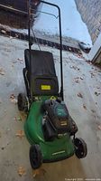 Photo of green Certified 150cc gas lawnmower showing front and top view with engine and handlebar visible.