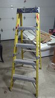Full view of the Featherlite yellow step ladder showing five steps and the metal top tray with paint marks.