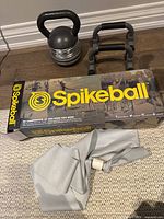 Lot includes adjustable kettlebell, push-up bars, Spikeball set box, and resistance band on floor.