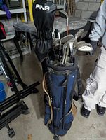 Golf clubs set in Bossi blue and tan stand bag with Ping driver headcover visible on one club.