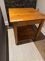 Knotted pine square side table showing the top surface with visible wood grain and some nicks.