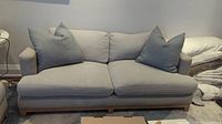 Front view of light grey sofa with two grey throw pillows