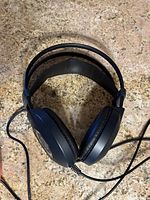 Full top view of the AKG K99 headphones showing cushioned ear pads and double headband design on stone surface.