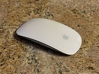 Top view of the white Apple Magic Mouse showing smooth surface and Apple logo.