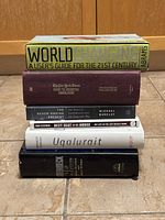 Stack of seven books on tiled floor showing titles and colors