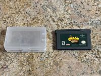 Crash Bandicoot game cartridge next to clear protective plastic case, both placed on a stone surface.