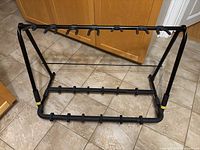 Front and angled side view of the black Hercules folding guitar stand showing all guitar holders and foldable frame.